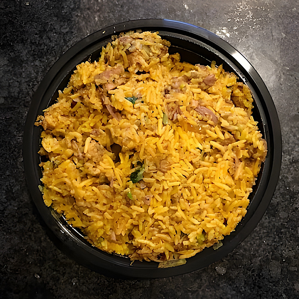 Overhead view of a black bowl filled with golden Indian biryani rice and meat.